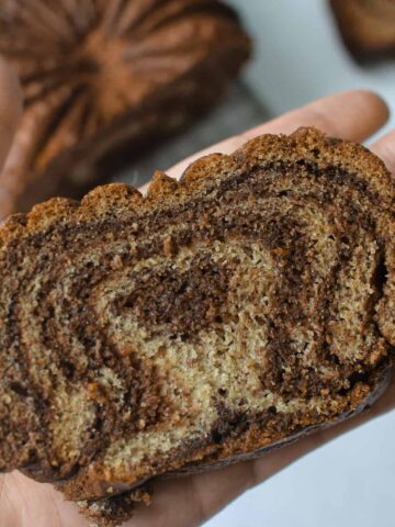 a slice of Banana Nutella Bread in hand, with loaf behind