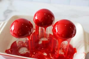 Red mirro glaze on mousse cakes dripping into baking dish