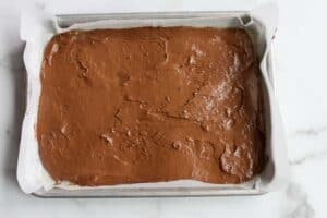 Devil's Food Cake batter smoothed out in a small baking sheet lined with parchment paper