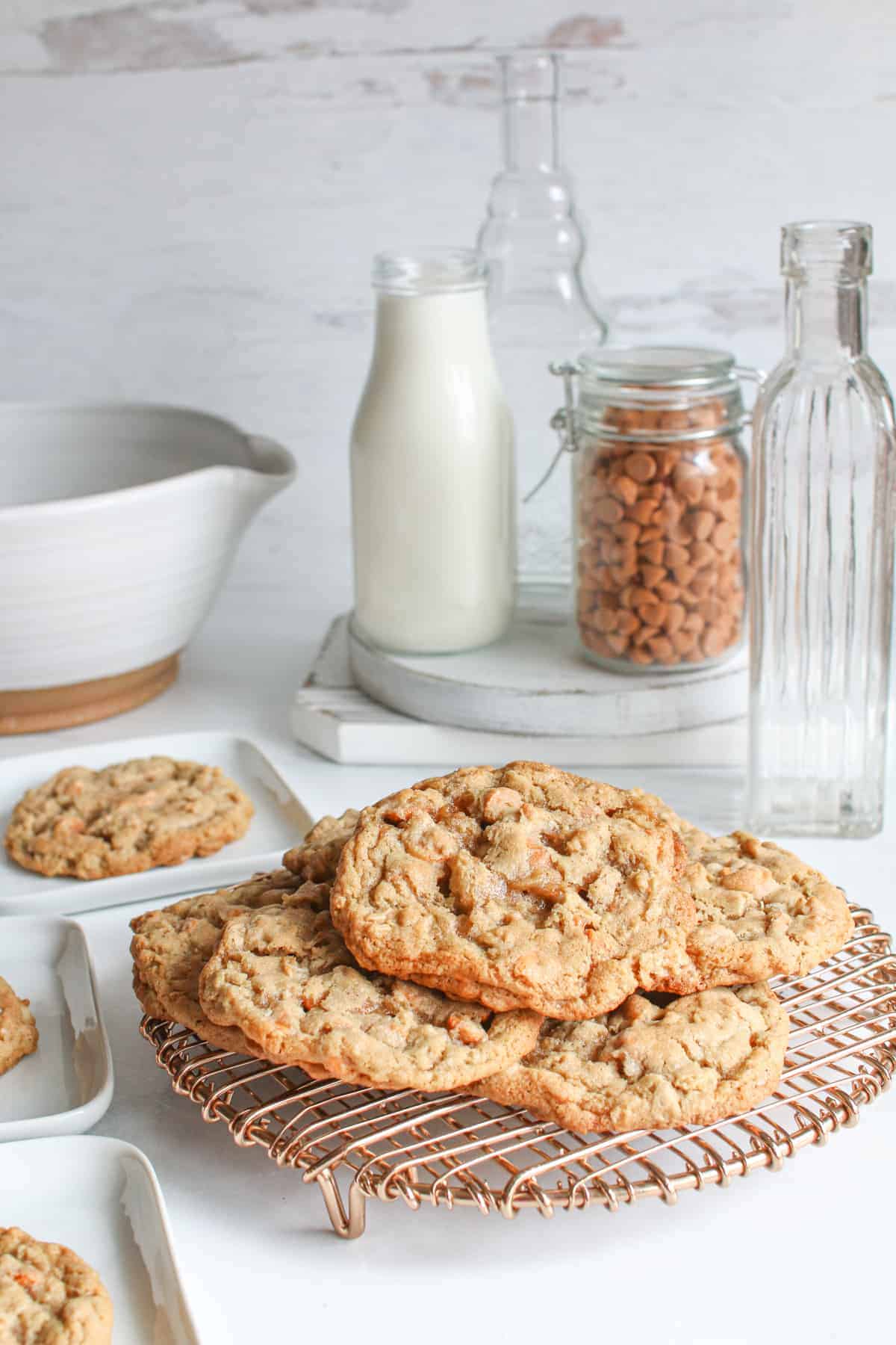 High Altitude Butterscotch Oatmeal Cookies on a copper wire trivet. More cookies are on small white square plates. 