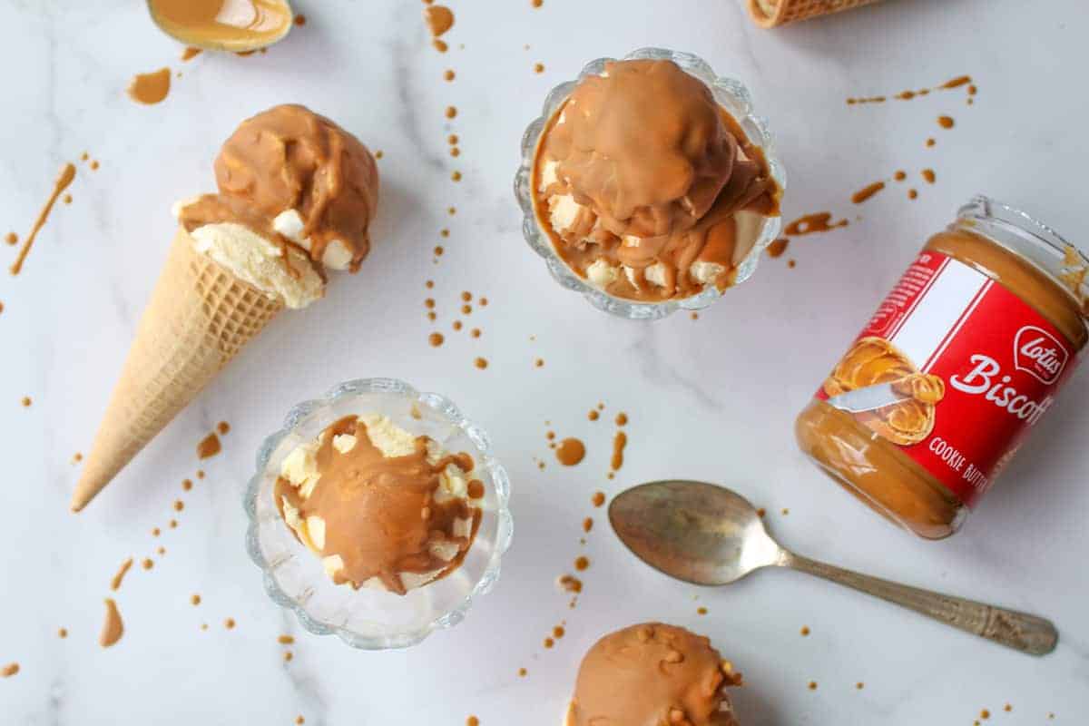 Cookie Butter Shell on Ice Cream in bowls and in cones with cookie butter jar on white marble