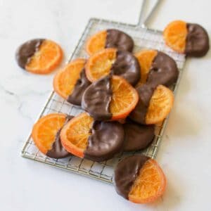 Chocolate Dipped Orange Slices stacked on a small metal grate on a white marble background
