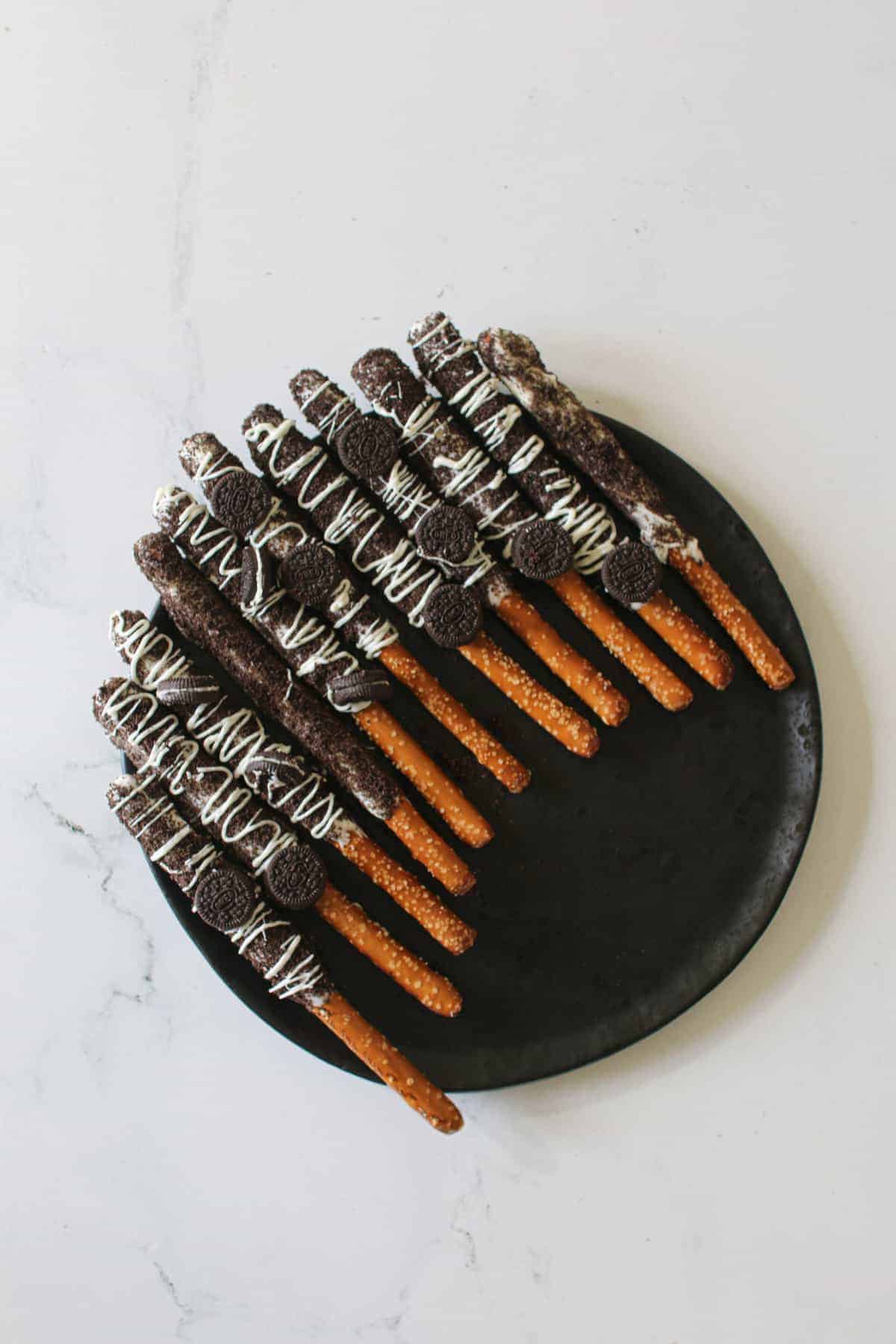 11 Cookies and Cream Pretzels on a place plate slightly angled on a white marble background.