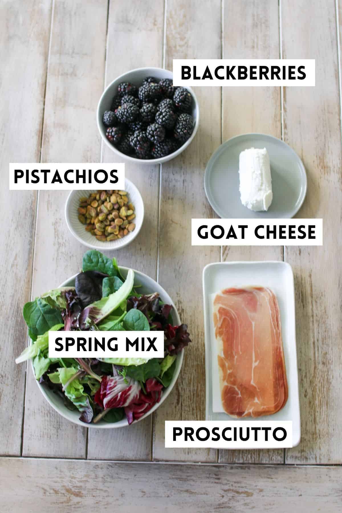 Blackberry Goat Cheese Salad in individual dishes on a light brown plank background. Each item is labeled with a white rectangle with black text.