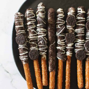 Cookies and Cream Pretzels on a black plate on a white marble background.