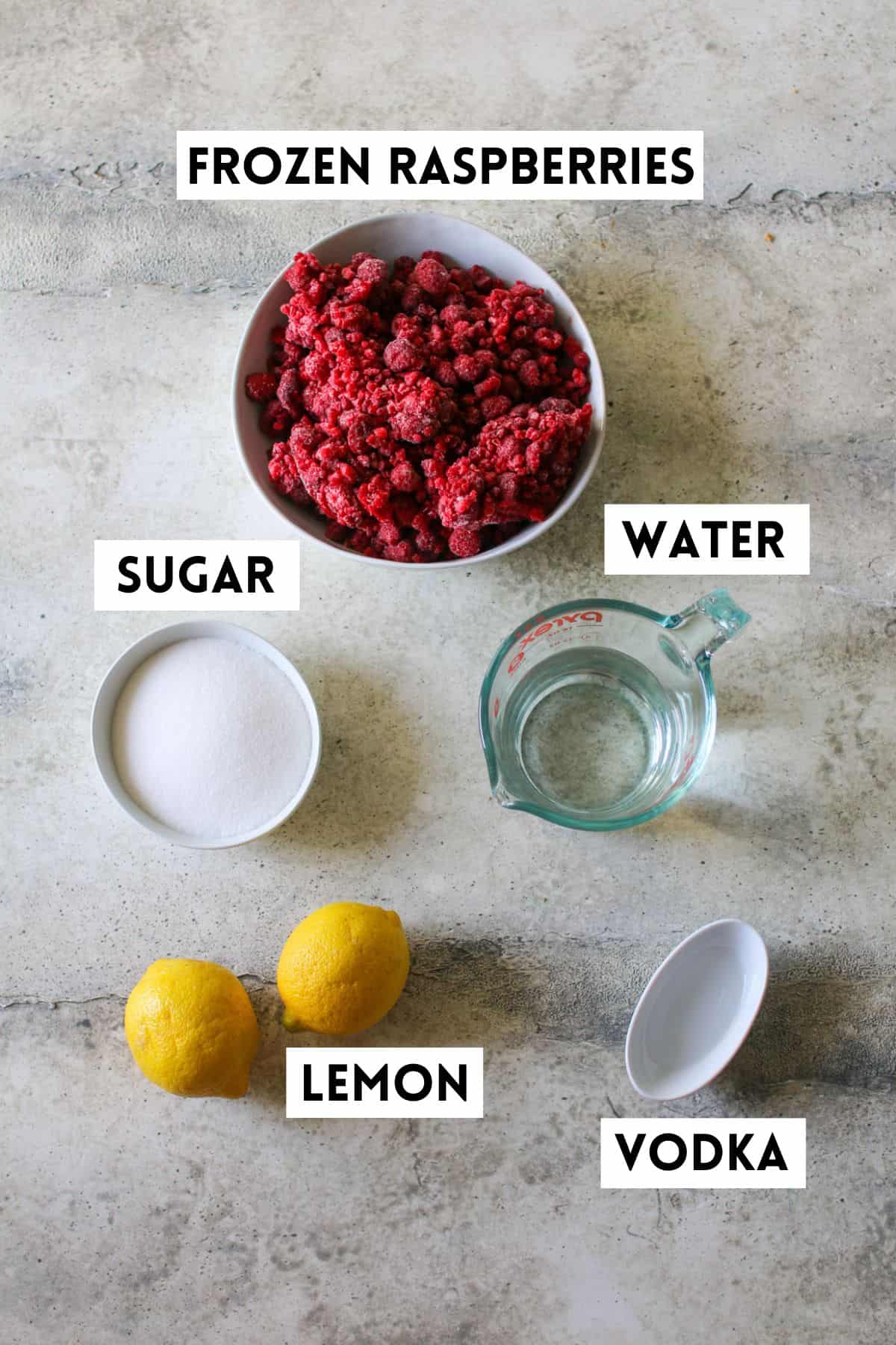 Raspberry Lemonade Sorbet ingredients on a stone background. Each ingredient is labeled with a white rectangle box with black font in all caps.
