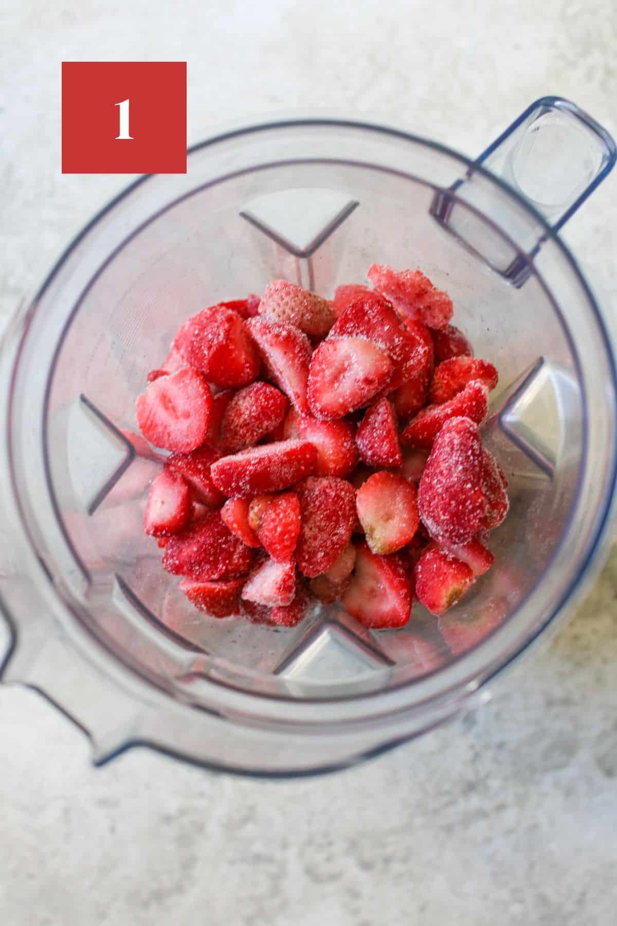 Sliced frozen strawberries in a blender body on a stone background. In the upper left corner is a dark red square with a white '1' in the center.
