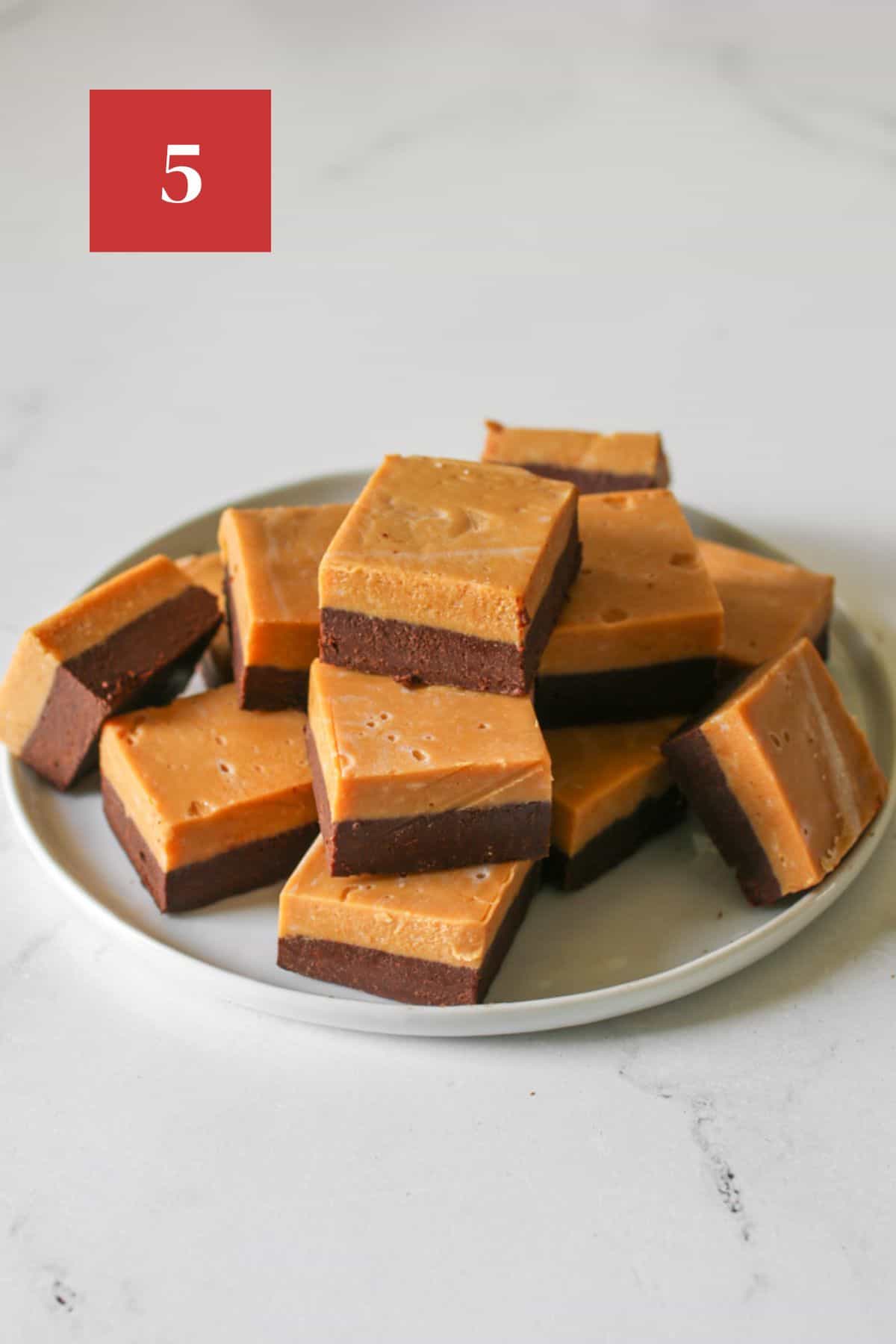 Sliced and stacked dulce de leche fudge on a white plate on a white background. In the upper left corner is a dark red square with a white '5' in the center.